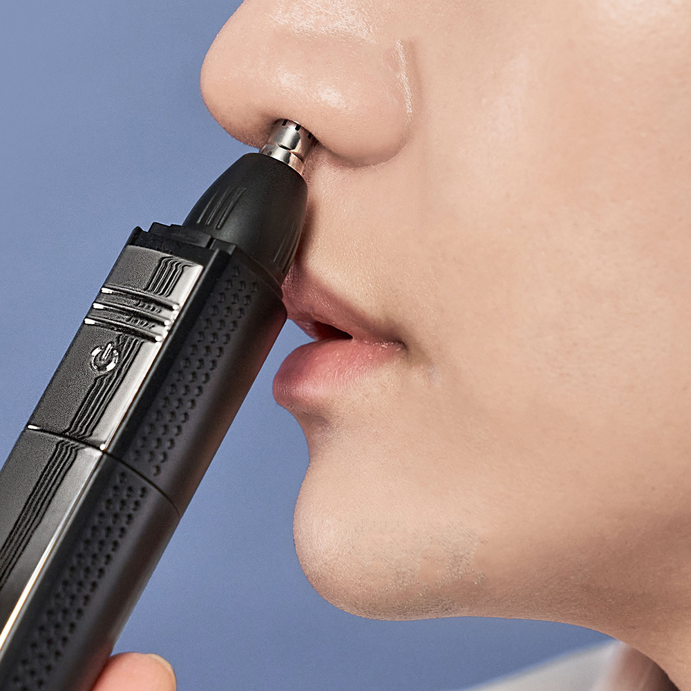 코에 트리머를 대고 있는 남성의 측면 모습으로 코털 제모 사용법을 보여주는 사진