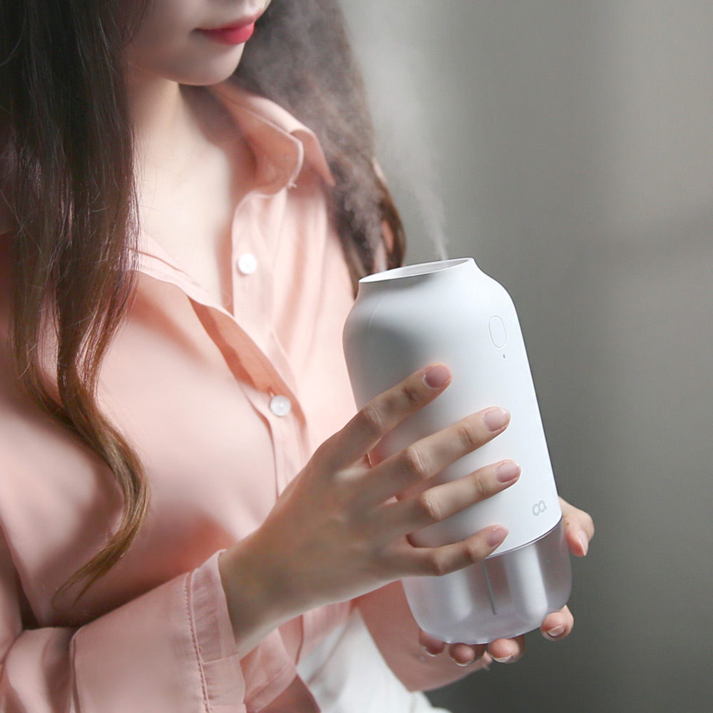 분홍색 셔츠를 입은 여성이 손에 들고 있는 가습기의 탁상용 휴대형 크기를 보여주는 사진