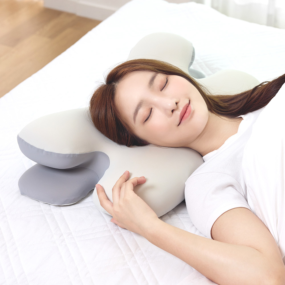 침대에 누워 흰색 경추 베개 커버를 안고 숙면 중인 여성의 실사용 장면