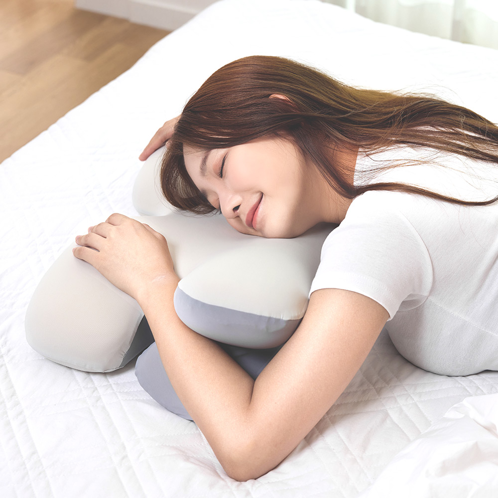 흰색 커버를 씌운 경추베개에 편안하게 누워 숙면을 취하는 여성