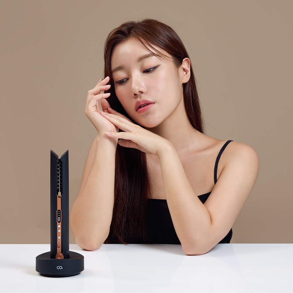 미니 고데기를 수직으로 세운 받침대에서 충전하는 모습을 보여주는 제품 사진