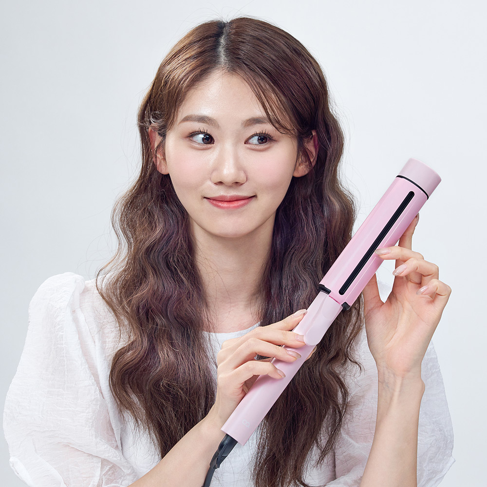 웨이브 스타일링이 완성된 긴 머리카락과 함께 핑크색 봉고데기를 들고 있는 완성 사진