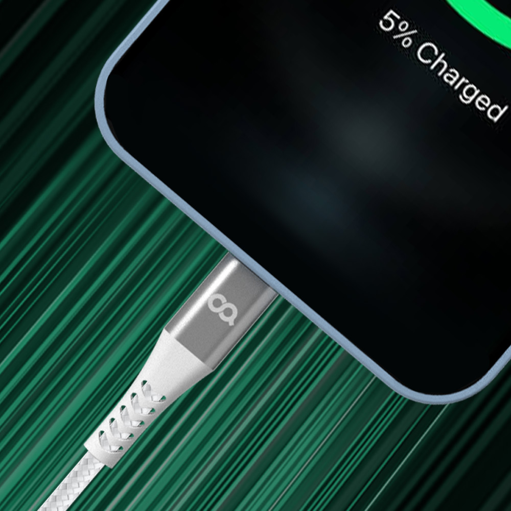 흰색 나일론 소재의 USB 충전 케이블이 녹색 줄무늬 배경 위에 놓인 스마트폰에 연결되어 있는 모습