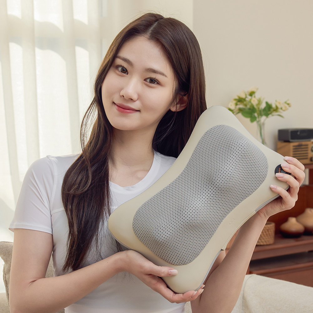 베이지색 무선 마사지 쿠션을 양손으로 들어 보이는 여성의 정면 모습