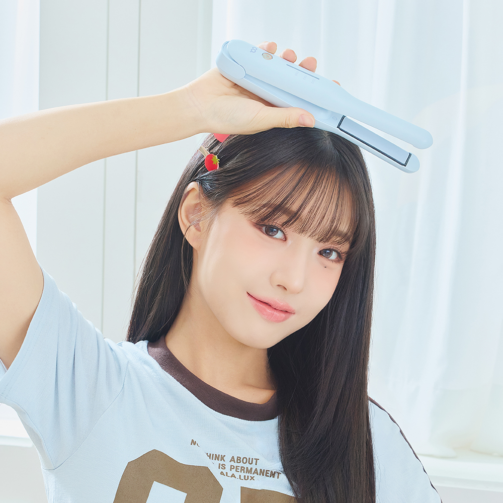 연한 하늘색 무선 미니 고데기를 손에 들고 앞머리에 대고 있는 모습