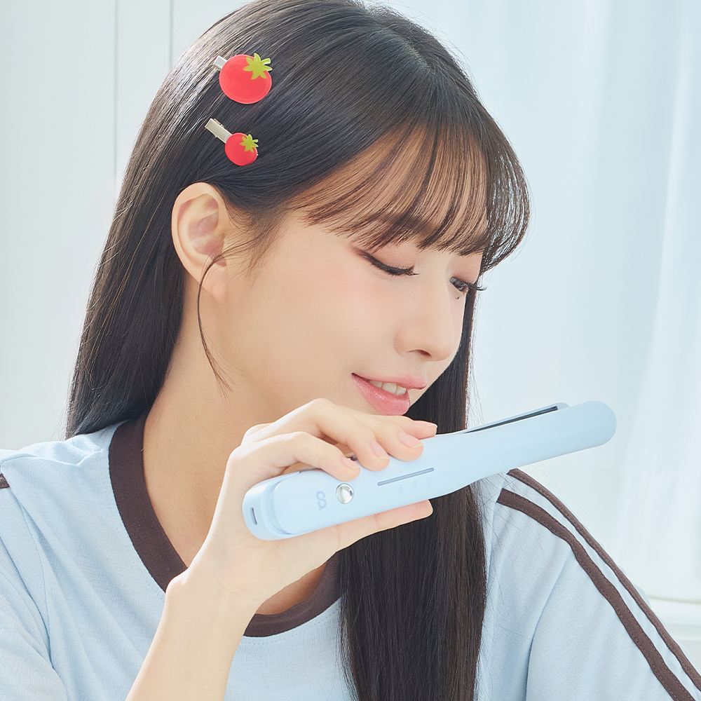 밝은 파란색 미니 고데기를 손에 들고 앞머리와 옆머리를 펴주는 여성의 스타일링 모습