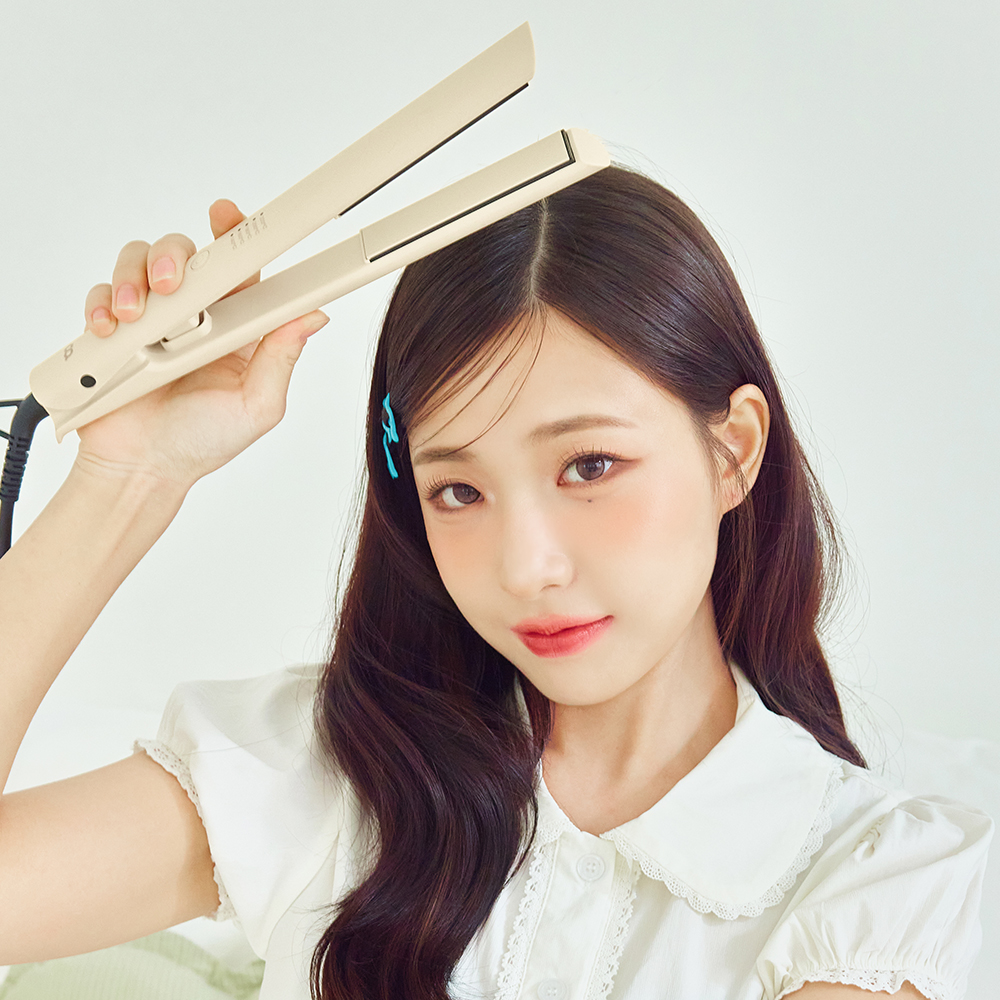 앞머리를 스트레이트로 정리한 모델이 베이지색 판 고데기를 손에 들고 포즈를 취하는 사용 장면